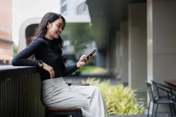 Person using a mobile phone while managing finances for a WEOKIE Membership Savings Account