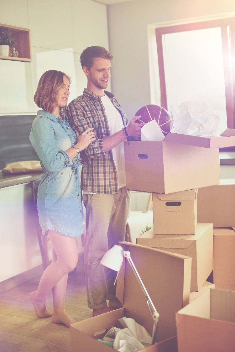 AdobeStock_231355048  Couple unpacking cardboard boxes in their new home. Young couple.-1