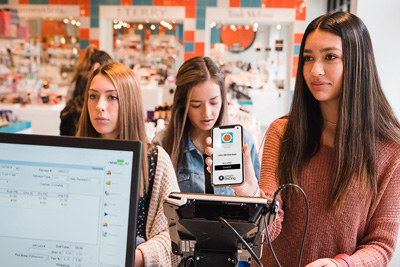 Group of women using BaZing app at the register. 
