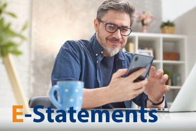 E-Statements - A man smiling as he checks is bank statement on his mobile phone.