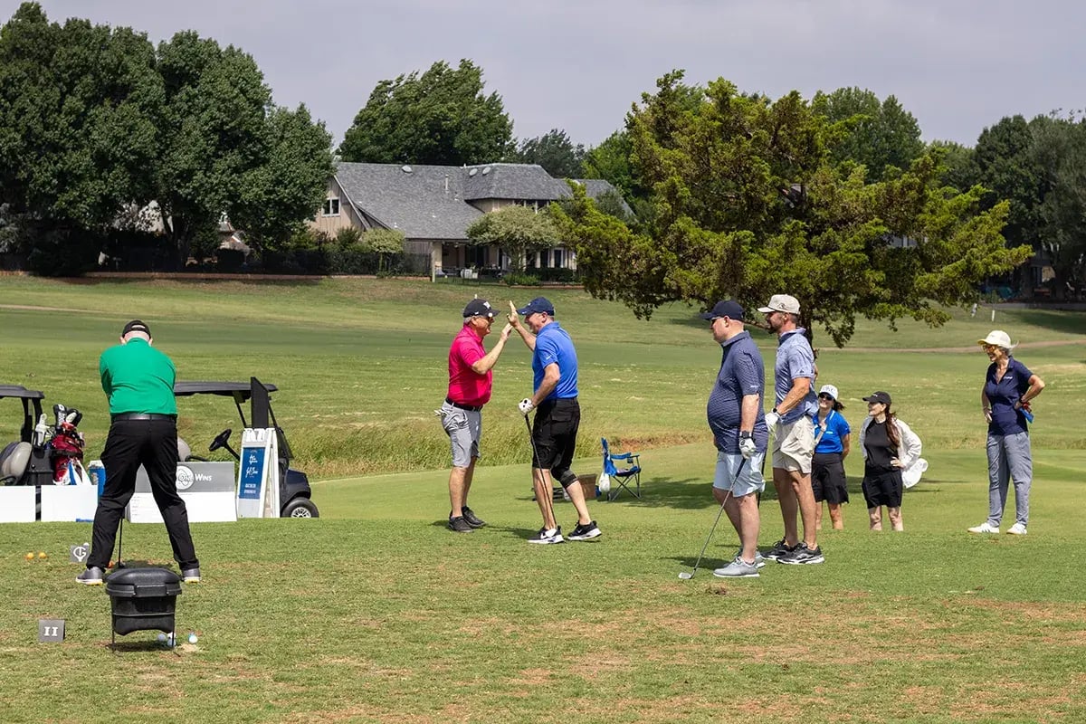 Participants high-fiving on the course during the 20th Annual WEOKIE Foundation Golf Classic