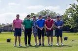 A group of participants posing for a photo on the golf course at the WEOKIE Foundation event