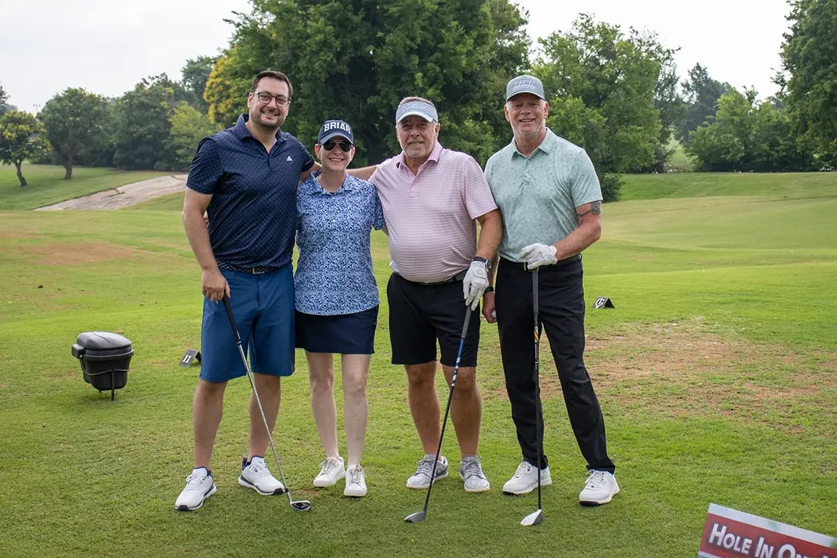 A group of participants posing for a photo on the golf course at the WEOKIE Foundation event