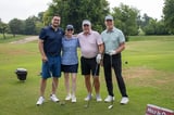 A group of participants posing for a photo on the golf course at the WEOKIE Foundation event