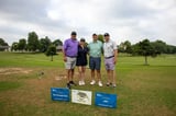 A group of participants posing for a photo on the golf course at the WEOKIE Foundation event