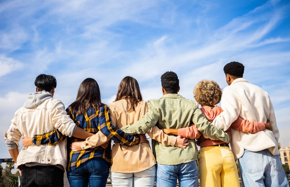 Group of friends standing together with arms linked, symbolizing unity and protection.