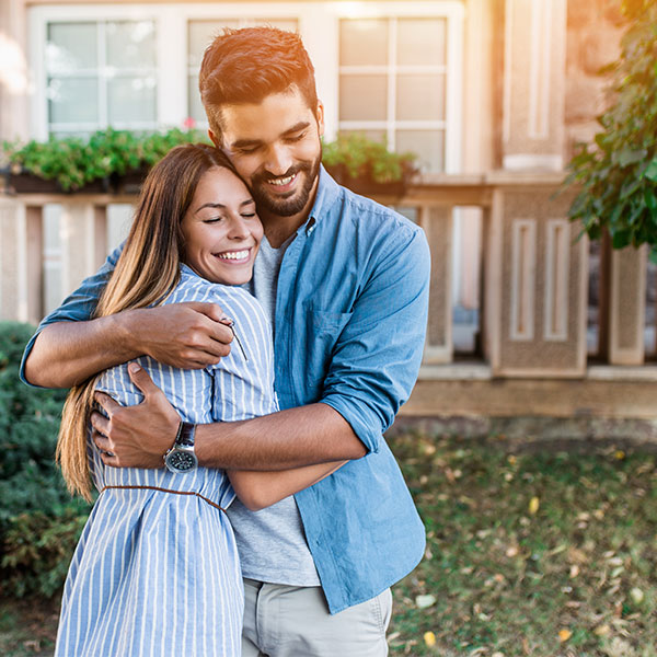 Young-Couple-Hugging-in-Front-Yard