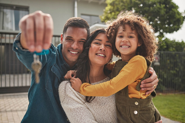 Family holding house keys outside a home
