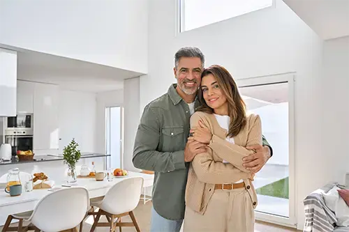 Smiling couple standing inside a large home