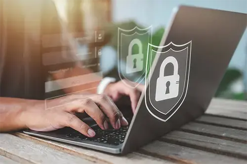 Person typing on a laptop at a secure login screen with digital padlock and shield icons
