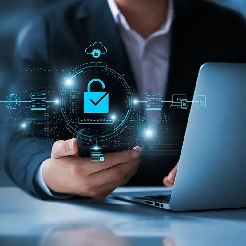 Professional holding a smartphone next to a laptop displaying glowing cybersecurity lock and data encryption icons