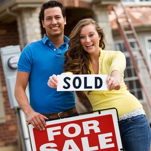 AdobeStock_151248668 couple with sold sign in front of house-1-1