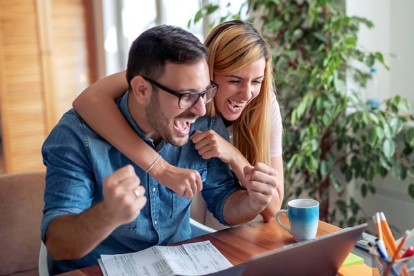A couple celebrating while looking at a laptop, highlighting the benefits of an ultimate checking account.