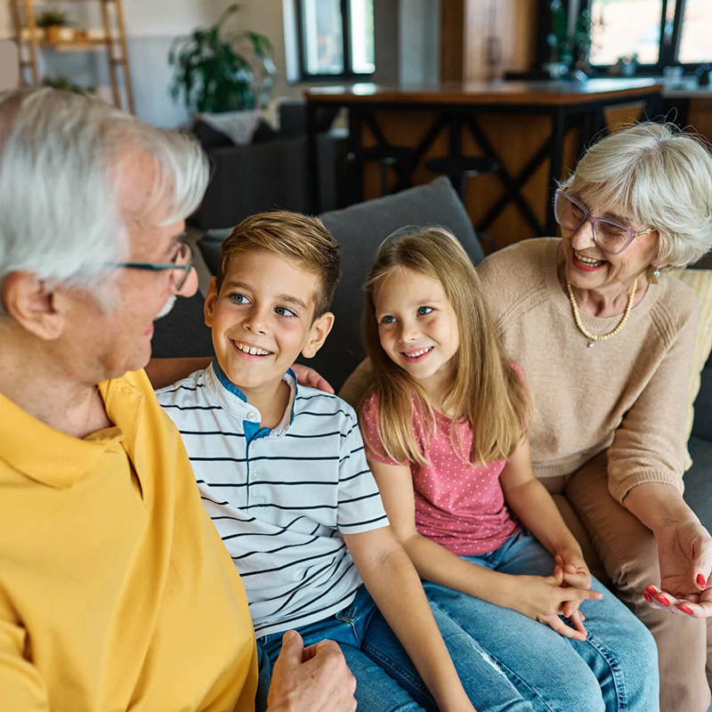 Grandparents and grandchildren laughing together, illustrating the long-term benefits of family savings and financial planning.