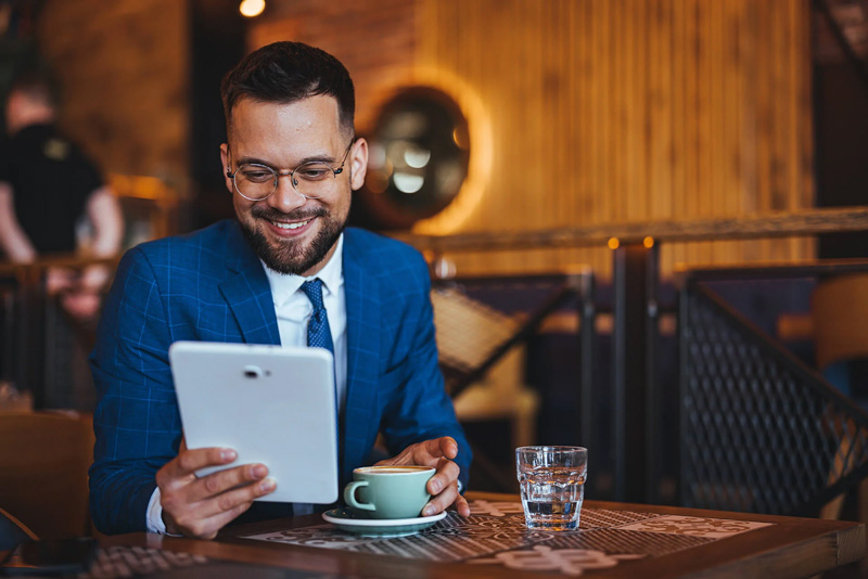 Person using a tablet to review savings account information at a cafe