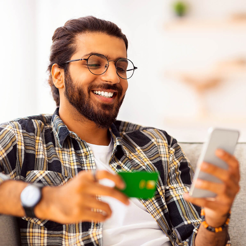Young man using a WEOKIE Visa debit card and mobile phone for a secure transaction.